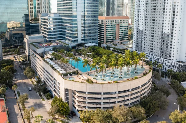 aerial view of modern Miami buildings, skyscrapers, pool areas with tropical plants, blue sky
