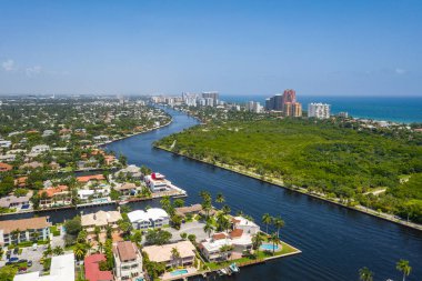 Arka planda modern binalar, mavi gökyüzü, mavi okyanus, yüzme havuzları, palmiye ağaçları olan Miami sahillerinin insansız hava aracı görüntüsü.