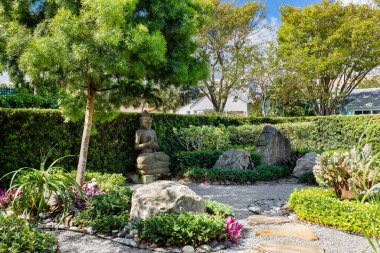 Bol bitki örtüsü, zen süslemeleri, torii kemeri, ateş çukuru, açık sandalyeler, taş yataklar, palmiyeler, ağaçlar