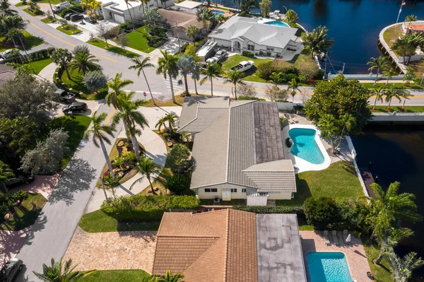 Aerial image of a residential neighborhood, houses with swimming pools, cars, boats, bridges, tropical plants, palms in pompano beach FL USA Miami beach drone view