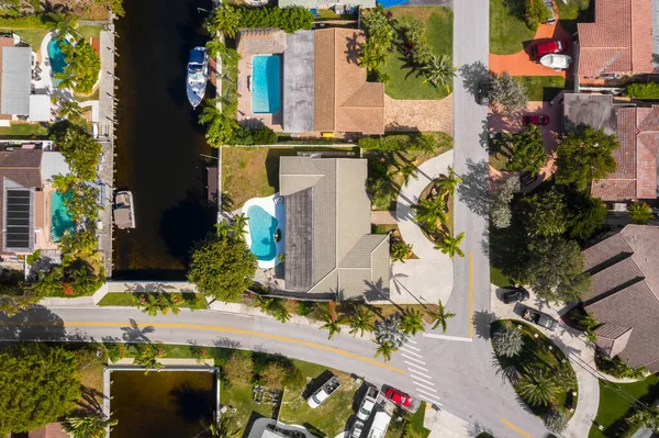 Aerial image of a residential neighborhood, houses with swimming pools, cars, boats, bridges, tropical plants, palms in pompano beach FL USA Miami beach drone view