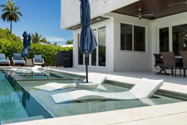 Havuzu, sörf tahtaları, şemsiyeli şezlonglar, palmiyeler, Miami Körfezi kanalı, rıhtımı, tekneleri olan zarif ve modern bir ev.,