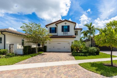 Miami 'nin Pembroke Pines banliyösündeki sömürge evi cephesi kaldırım, tropik bitkiler, kırmızı çatı kiremitleri, palmiye ağaçları, mavi gökyüzü.