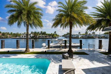 Barselona Kanalı 'na bakan modern lüks evin arka bahçesi Fort Lauderdale, Miami' de, güneşli havuz, açık koltuklar, fayans zemin.