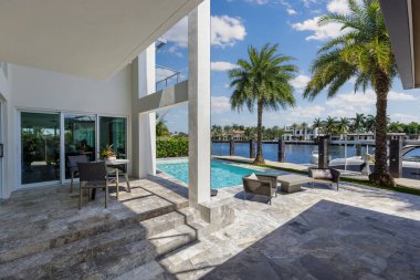 Barselona Kanalı 'na bakan modern lüks evin arka bahçesi Fort Lauderdale, Miami' de, güneşli havuz, açık koltuklar, fayans zemin.