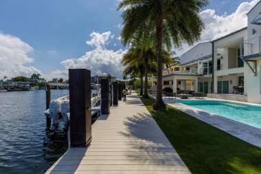 Barselona Kanalı 'na bakan modern lüks evin arka bahçesi Fort Lauderdale, Miami' de, güneşli havuz, açık koltuklar, fayans zemin.