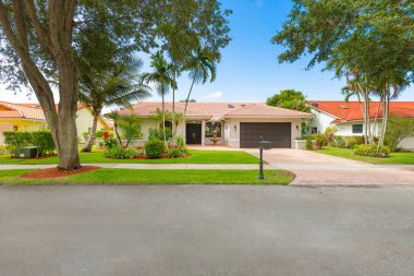 Boca Raton, Miami 'deki apartman cephesi, tropik bahçeler, kısa çimenler, kaldırım, cadde, kiremit kaplı çatı, mavi gökyüzü.