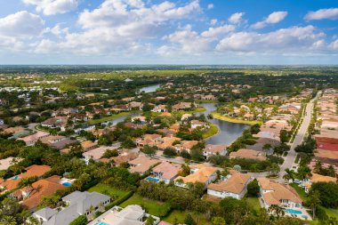 Miami Florida Delray Sahili 'nin banliyölerine insansız hava aracı görüntüsü. Büyük tropikal bitki örtüsü, fayanslı evler ve mavi gökyüzü var.