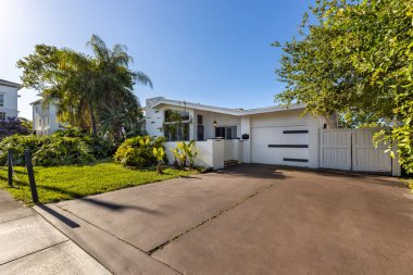 Beyaz modern ev cephesi, garaj, ön bahçe, kısa çimler, palmiyeler, tropik bitkiler, bulutsuz mavi gökyüzü