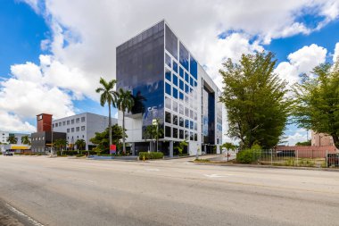 Ofis binası cephesi, Miami 'deki Flagami mahallesinde uluslararası havaalanı yakınında, büyük aynalı pencereler, mavi gökyüzü, park alanı.