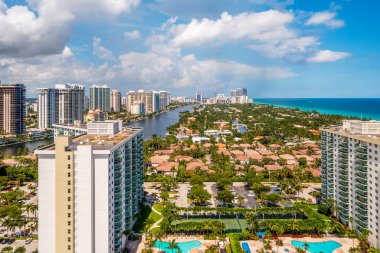 Şehirdeki hava aracı manzarası güneşli adalar, evleri, kuleleri, deniz manzarası, tropikal bitki örtüsü ve mavi gökyüzü olan binalar.