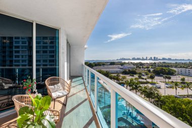 Miami 'deki North Bay Village' ın balkonundan, modern binalar ve kuleler, köprüler, deniz, açık sandalyeler, turkuaz camlı beyaz parmaklıklar
