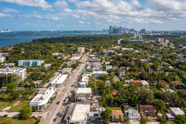 Aerial shot of Upper East Side residential neighborhoodin Miami, lush vegetation is seen, modern buildings, luxury houses, urban skyline, blue sky, street with cars