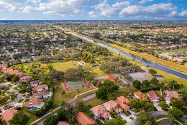 Deerfield Sahili 'nin hava aracı görüntüsü, lüks evler, malikaneler, yeşil alanlar, su kanalları, palmiyeler, ağaçlar, kısa çimenler, kırmızı çatı fayansları