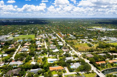 Aerial drone view of the Pinecrest villa in Miami-Dade, parking area, tropical vegetation, with many trees and palms, luxury and modern buildings and houses
