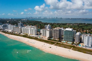 Beautiful view of spa with wooden floor with beach and sea in the background, tropical plants are also observed around, palms, modern buildings, blue sky