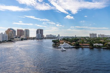 Aerial drone shot of the Central Beach neighborhood in Fort Lauderdale, where we see abundant tropical vegetation, modern buildings, rivers, boats, houses facing the water, blue sky with clouds