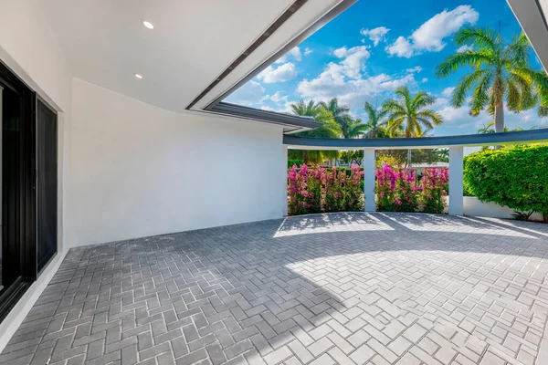 Beautiful backyard of elegant modern house in Nautilius neighborhood of Miami Beach, flower wall, cement floor, columns, tropical trees and plants, blue sky in the background