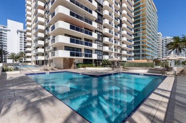 Beautiful swimming pool, with sun loungers, umbrellas,  palms, sea in the background with tropical  landscape