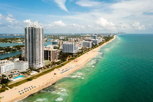 Aerial drone view of the North Beach beaches in Miami Beach, building known as Akoya, turquoise sea, umbrellas, modern buildings and towers around, blue sky