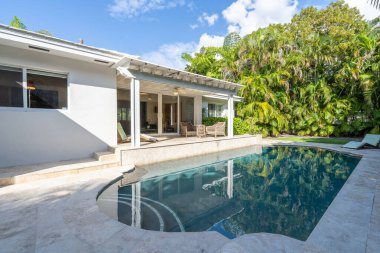 Beton zemin ve havuzu olan güzel bir bahçe, tropikal bitkilerle çevrili, güneşli verandalı, açık mobilyalı, sarmaşıklı, Coral Gables 'da yer alan