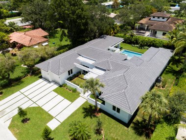 Miami-Dade 'deki zarif ve modern bölgenin hava aracı görüntüleri, beyaz duvarlar, modern evler, kısa otlar, yüzme havuzları, ağaçlar ve palmiye ağaçları.