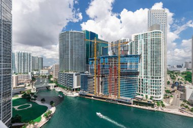 Brickell Key bölgesinin insansız hava aracı görüntüleri, bir sürü kule ve modern binalar, ticari şehir manzarası, deniz ve kanallarla çevrili, yelkenliler, rıhtımlar, köprüler, caddeler, mavi gökyüzü ve turkuaz deniz.
