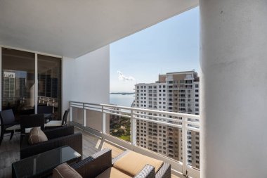 Brickell Key bölgesinin balkon görüntüsü, bir sürü kule ve modern bina, ticari şehir manzarası, deniz ve kanallarla çevrili, yelkenli, rıhtım, köprüler, caddeler, mavi gökyüzü ve turkuaz deniz