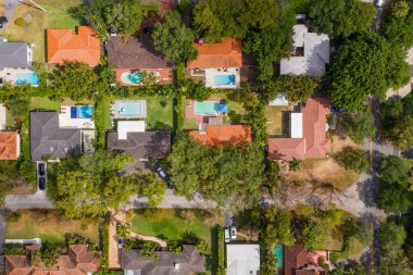 Klasik bir evin güzel cephesi, bej duvarlar, kırmızı fayanslar, kapı, pencere, garaj, kaldırım, kısa çimen, yapraklı ağaçlar, arka planda mavi gökyüzü gibi beyaz açıkların detayları.