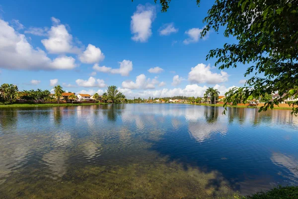 Miami-Dade, FI, ABD 'de bulunan Miami yerleşim alanındaki göldeki güzel su aynası klasik banliyö tarzı evler, tropikal iklim, mavi gökyüzü.