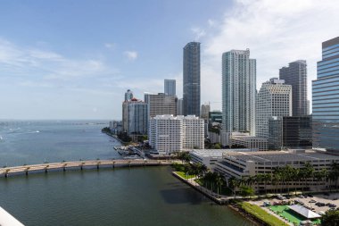 Brickell Key bölgesinin insansız hava aracı görüntüleri, bir sürü kule ve modern binalar, ticari şehir manzarası, deniz ve kanallarla çevrili, yelkenliler, rıhtımlar, köprüler, caddeler, mavi gökyüzü ve turkuaz deniz.