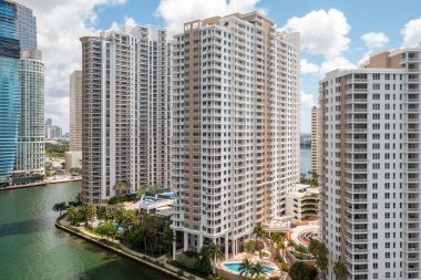 Brickell Key bölgesinin balkon görüntüsü, bir sürü kule ve modern bina, ticari şehir manzarası, deniz ve kanallarla çevrili, yelkenli, rıhtım, köprüler, caddeler, mavi gökyüzü ve turkuaz deniz