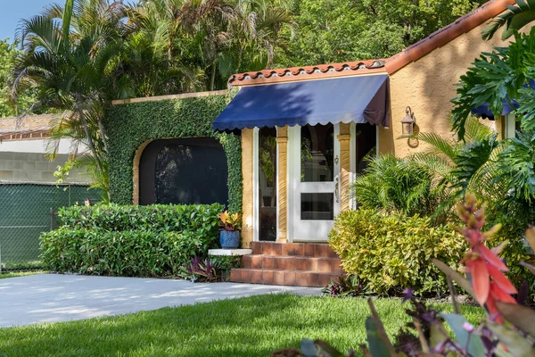 stock image Classic style house facade in the Granada neighborhood in Coral Gables, Miami; FL, USA,Surrounded by large vegetation and vines on the walls, palms, driveway, front door, short grass