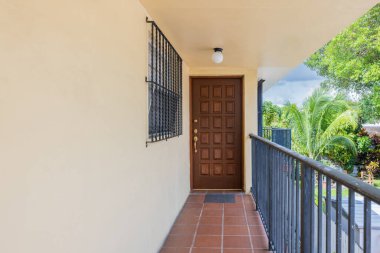 Modern klasik evin arka bahçesi banliyö Coral Gables 'da, kısa çimenler, ahşap çitler, bej mülk, döşeme, kiremit çatı, palmiye ağaçlarıyla çevrili arsa.