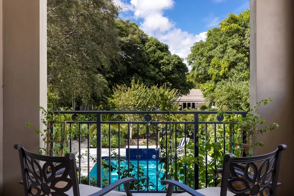 stock image Backyard of elegant and luxurious mansion, with palms and lots of plants around, beautiful pool, covered patio, outdoor furniture, shortgrass, basketball court and blue sky with clouds