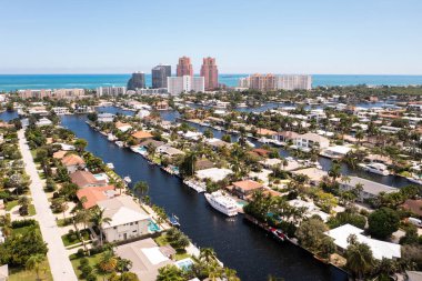 Coral Ridge mahallesinin, Fort Lauderdale, Miami, ABD 'deki ticari alanının, kanalların ve teknelerin, lüks evlerin ve malikanelerin, bol tropikal bitki örtüsünün, mavi gökyüzünün havadan çekilmiş görüntüsü.