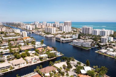 Coral Ridge mahallesinin, Fort Lauderdale, Miami, ABD 'deki ticari alanının, kanalların ve teknelerin, lüks evlerin ve malikanelerin, bol tropikal bitki örtüsünün, mavi gökyüzünün havadan çekilmiş görüntüsü.