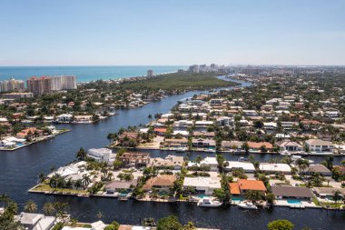 Coral Ridge mahallesinin, Fort Lauderdale, Miami, ABD 'deki ticari alanının, kanalların ve teknelerin, lüks evlerin ve malikanelerin, bol tropikal bitki örtüsünün, mavi gökyüzünün havadan çekilmiş görüntüsü.