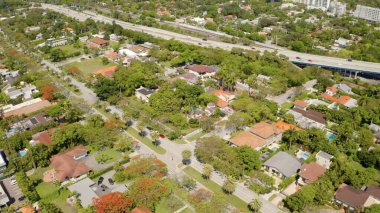 Miami, ABD 'de hava aracı vuruldu, ticari alan, lüks evler, binalar ve malikaneler, çevrede bol miktarda tropikal bitki örtüsü, mavi gökyüzü ve okyanus.