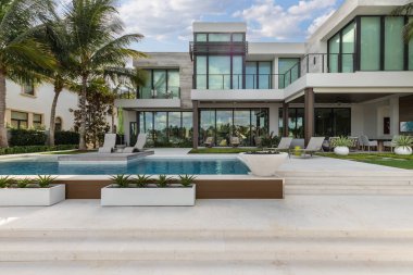 Florida, USA. Modern building with swimming pool, trees, chairs. Urban landscape with blue reflecting pool, city architecture, and scenic environment.