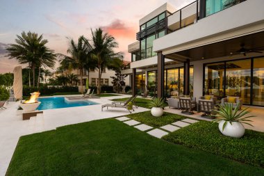 Florida, USA. Modern building with swimming pool, trees, chairs. Urban landscape with blue reflecting pool, city architecture, and scenic environment.
