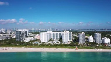 Florida, ABD 'deki hava aracı görüntüleri, ticari alan, lüks evler, binalar ve malikaneler, çevrede bol miktarda tropikal bitki örtüsü, mavi gökyüzü ve okyanus.