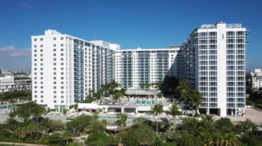 Florida, ABD 'deki hava aracı görüntüleri, ticari alan, lüks evler, binalar ve malikaneler, çevrede bol miktarda tropikal bitki örtüsü, mavi gökyüzü ve okyanus.