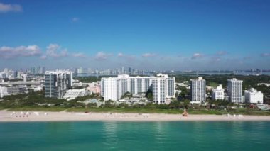 Florida, ABD 'deki hava aracı görüntüleri, ticari alan, lüks evler, binalar ve malikaneler, çevrede bol miktarda tropikal bitki örtüsü, mavi gökyüzü ve okyanus.