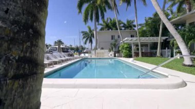 Florida, USA. Modern building with swimming pool, trees, chairs. Urban landscape with blue reflecting pool, city architecture, and scenic environment.