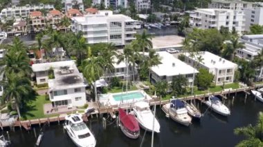 Florida, ABD 'deki hava aracı görüntüleri, ticari alan, lüks evler, binalar ve malikaneler, çevrede bol miktarda tropikal bitki örtüsü, mavi gökyüzü ve okyanus.