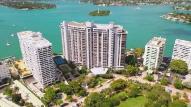Miami, Florida, ABD 'de hava aracı çekimi, ticari alan, lüks evler, binalar ve malikaneler, çevrede bol miktarda tropikal bitki örtüsü, mavi gökyüzü ve okyanus.