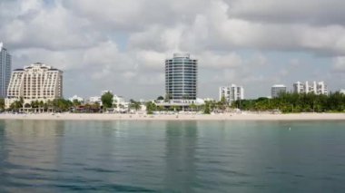 Florida, ABD 'deki hava aracı videosu, ticari alan, lüks evler, binalar ve malikaneler, mavi gökyüzü, okyanus ve tekneleri olan güzel bir sahilde bol miktarda tropikal bitki örtüsü..