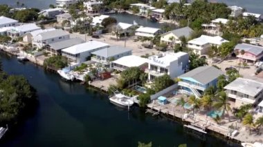 Florida, ABD 'deki hava aracı videosu, ticari alan, lüks evler, binalar ve malikaneler, mavi gökyüzü, okyanus ve tekneleri olan güzel bir sahilde bol miktarda tropikal bitki örtüsü..