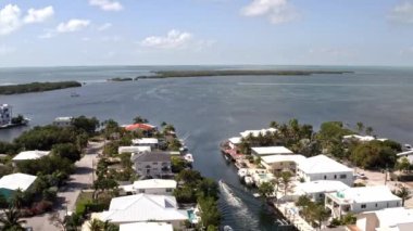 Florida, ABD 'deki hava aracı videosu, ticari alan, lüks evler, binalar ve malikaneler, mavi gökyüzü, okyanus ve tekneleri olan güzel bir sahilde bol miktarda tropikal bitki örtüsü..